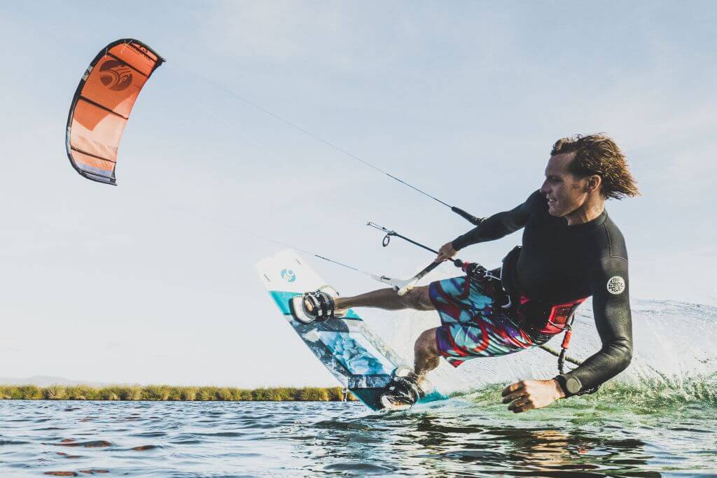 Kitesurfer in Aktion auf ruhigem Wasser, während er eine Kitesurf-Lektionen genießt.