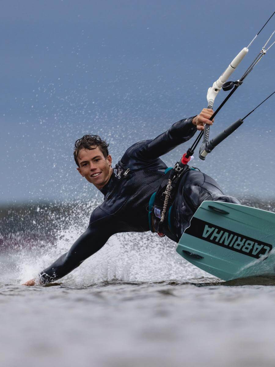 Kitesurfer in Action: Dynamische Welle, sportliches Equipment, ideal für passionierte Wassersportler. Online Surfshop.