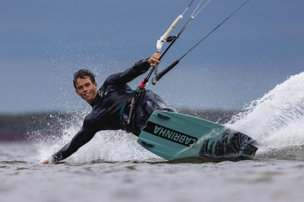 Kitesurfer in action auf dem Wasser, Energie und Dynamik unter dunklem Himmel.