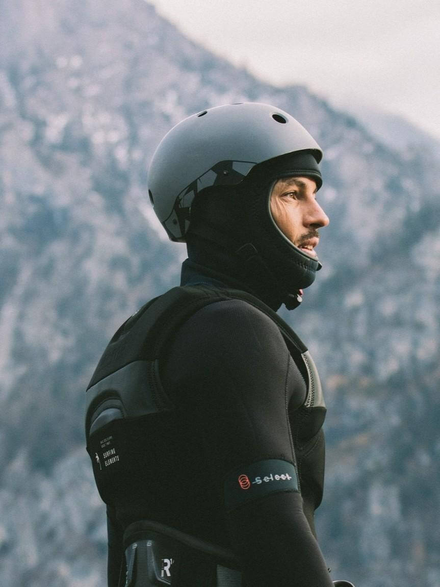 Surfer mit Helm und Neoprenanzug, bereit für Wassersport in den Bergen, ideal für einen Online Surfshop.