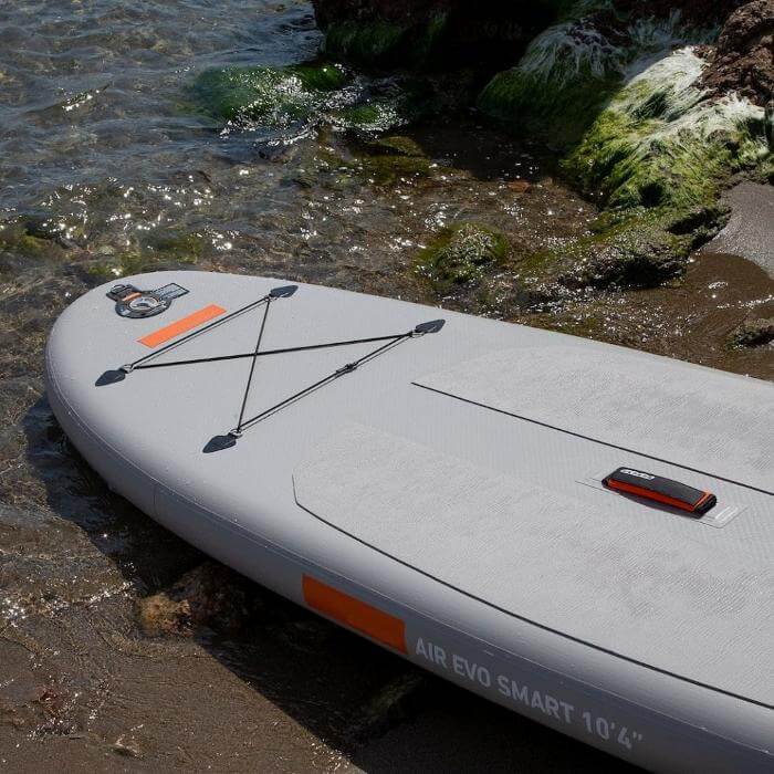 Aufblasbares Paddleboard AIR EVO SMART 10'4" am Strand, ideal für Wassersport und Abenteuer.