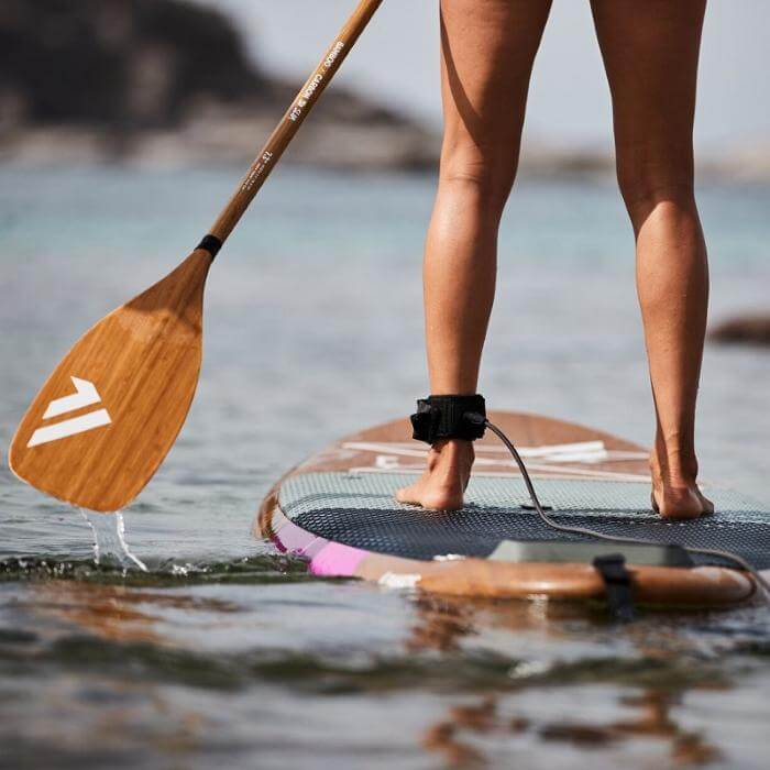 Person auf einem Stand-Up Paddle Board mit Paddel im Wasser, ideal für Wassersport und Outdoor-Aktivitäten.