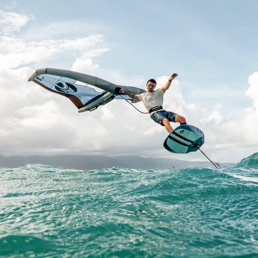 Mann beim Foil-Wing-Surfen auf den Wellen, mit Himmel und Wolken im Hintergrund.